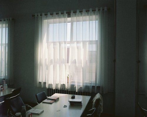 Desk positioned perpendicularly to a bright window with sheer curtains