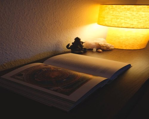 Cozy reading corner with warm lamp light falling on open book pages